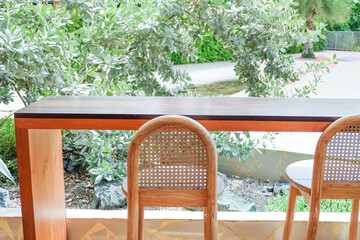 Obraz premium Wicker chair and wooden table in restaurant,Rattan chair in scandinavian interior of living room,Mediterranean minimal wall and green plant exterior architecturer,warm beige tones,copy space.