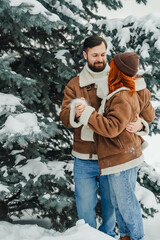 Love romantic couple lovestory. Brutal bearded man, bright red-haired girl woman in winter park. Romantic date, kissing, hugging. Walking, having fun. Stylish clothes, red sheepskin coat, jacket, hat