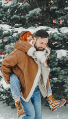 Love romantic couple lovestory. Brutal bearded man, bright red-haired girl woman in winter park. Romantic date, kissing, hugging. Walking, having fun. Stylish clothes, red sheepskin coat, jacket, hat