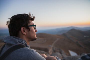 A young man watches the sunrise. He looks to the future with hope.