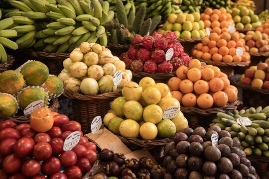 background with colorful baskets with tropical fresh fruits and vegetables at the market 