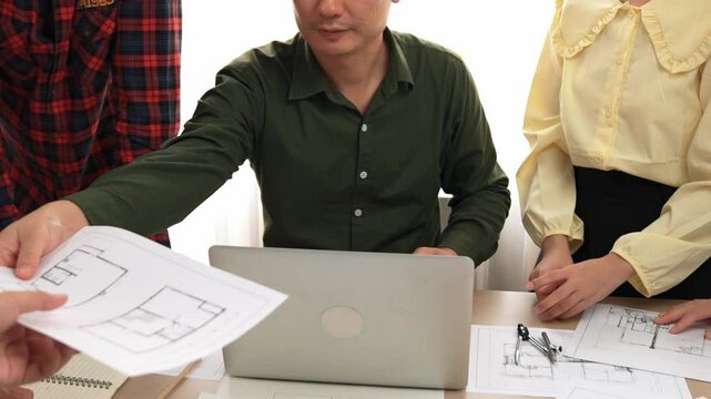 Smart architect and safety engineer discussion about building plan on table with architectural document, measurement tools and wooden block scatter around at modern office. Closeup. Delineation.