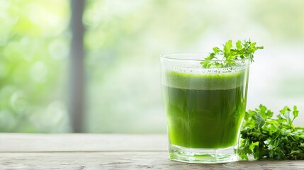   A glass filled with green liquid sits next to a pile of green leafy greens atop a wooden table