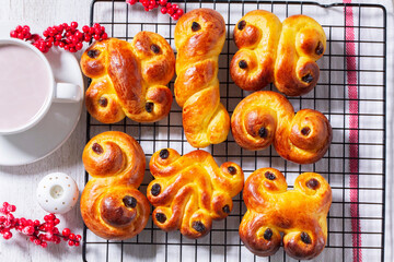 Traditional saffron Swedish buns lussekatt in different shapes, served with cocoa on a wooden...