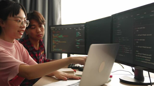 Slow motion back end software developer engineer for computer programming working together on debugging writing computing code, solving complex algorithms display on monitor in office. Burgeoning