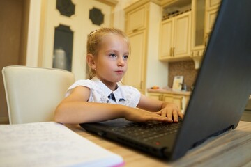 Young girl focused on her laptop while studying at a kitchen table