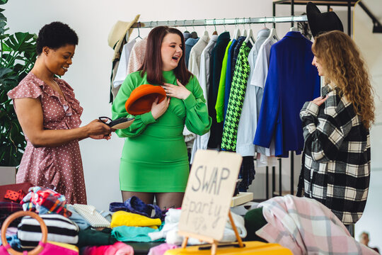 Girls having fun at home swap party. Garage sale, second hand, trying used clothes, exchanging jeans, dresses, accessories . Sustainable fashion, conscious consumption, circular economy concept