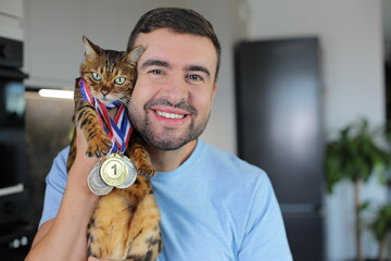 Man holding a cat that has won several medals 