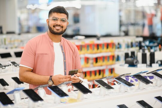 handsome young man buying new mobile in the electronic shop.