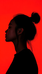 Red light silhouette of a woman with hair in a bun, profile view