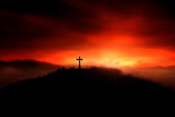 Silhouette of a cross on a hill with a dramatic red and orange sunset