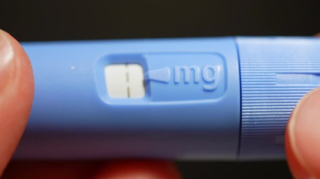 Diabetes Injector pen dosage of the medication display, macro close up. Drug for diabetes prevention and weight loss. View at injector pen in hands.