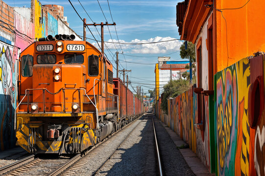 Graffiti-Lined Tracks Orange Train Crossing a Mexico-USA Border town