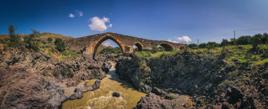 Ponte dei Saraceni. An ancient medieval bridge of Norman age located on the Simeto river. Adrano - Catania, in Sicily. Aerial drone picture. June 2023