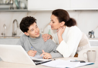 Obraz premium Boy does school homework with his mother and solves mathematical problems