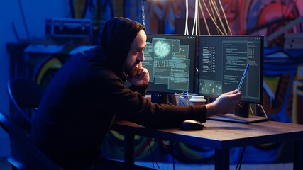 Malicious man hacking and talking on phone with partner, stealing credit card numbers, manipulating banking systems. Evil hacker runs dangerous code, chatting with friend in telephone call, camera B