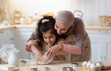 Loving Muslim Mom Teaching Daughter How To Knead Dough, Having Fun Together In Kitchen At Home, Woman In Hijab Helping To Her Little Child, Islamic Family Enjoying Making Homemade Pastry, Free Space