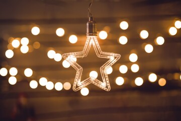 A glowing star shaped light hangs against a backdrop of warm  blurred lights.