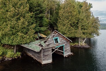 Fototapeta premium Abandoned ruined boathouse in the forest on the lakeshore at Lac Mercier, Mont-Tremblant, Quebec, Canada.