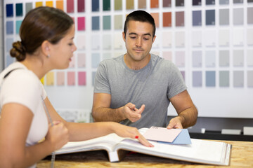 Seller of hardware store advises woman of the buyer what ceramic tiles to buy