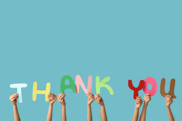 Female hands holding text THANK YOU made of paper on blue background