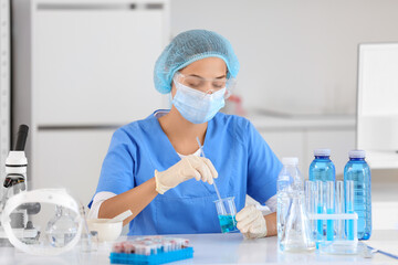 Female young scientist with professional glassware examining water quality in research laboratory