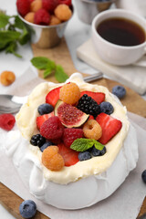Pavlova cake (meringue dessert) with whipped cream, fresh berries, fig and mint on table, closeup