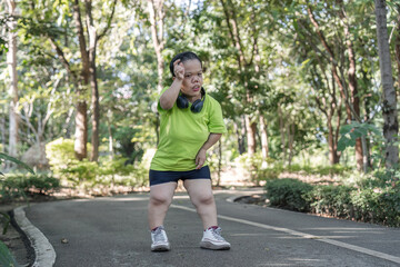 Exhausted Woman Jogging in Park Amidst Lush Greenery on a Sunny Day