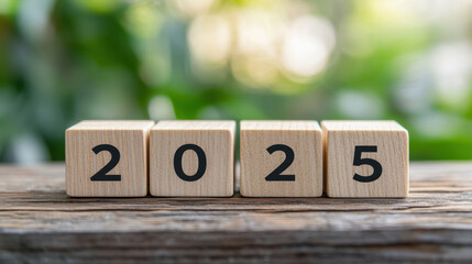 Wooden blocks displaying year 2025 on rustic surface, symbolizing future planning and optimism. blurred green background adds fresh touch