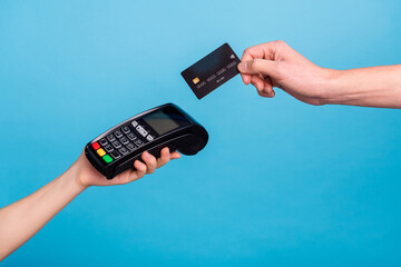 Cropped close up portrait of hands hols pos terminal credit card payment isolated on blue color...
