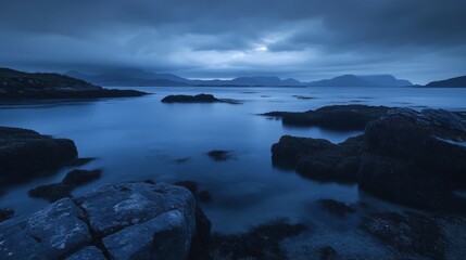 Serene twilight coastal scene with dark rocks and calm water.