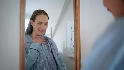 Young woman trying clothes looking mirror wardrobe closeup. Girl holding hanger