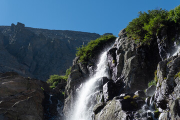 Obraz premium A stunning Timberline waterfall cascades down rocky cliffs in a Rocky mountain National Park