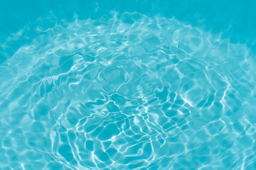 Obraz premium Blue water with ripples on the surface. Defocus blurred transparent blue colored clear calm water surface texture with splashes and bubbles. Water waves with shining pattern texture background.