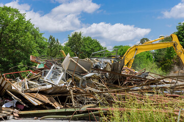 Heavy machinery is actively involved in construction demolishing structure amid lush landscape.