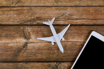 Airplane model rests on wooden table next to digital tablet, symbolizing fusion of travel modern technology in purchase online ticket