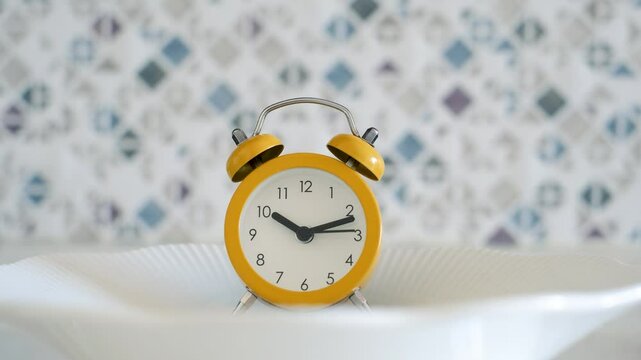 Empty plate with alarm clock front view, intermittent fasting concept.
