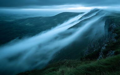 Obraz premium Fog rolling over green valley hills at dusk.