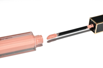A tube of lip gloss with a brush lies on a white background.