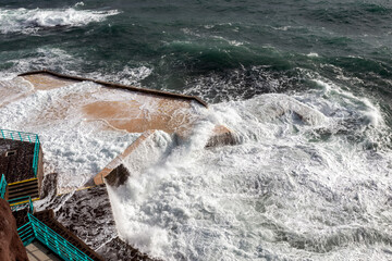 A stunning view of waves crashing dramatically against the coastal structures in Funchal, Madeira,...