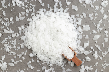 Obraz na płótnie Canvas Top view of magnesium flakes scattered from scoop. Natural sea salt as wellness or spa products for bath or relaxation, self-care or sustainable living, Wellness and Body Function Enhancement