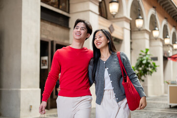 Fototapeta premium A charming, happy Asian couple in cozy clothes are enjoying shopping together at a mall.