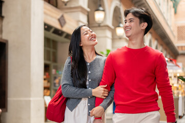 A beautiful young Asian woman enjoys shopping with her boyfriend at a mall on Christmas.