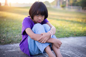 A sad little girl sitting alone outside