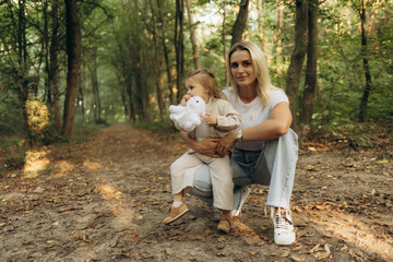Fototapeta premium Mother and daughter having fun in the park. Happy family concept. Beauty nature scene with family outdoor lifestyle. Happy family resting together. Happiness and harmony in family life.