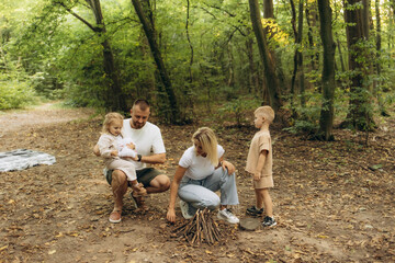 A young family with a fire is making a campfire