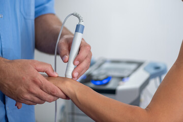 Physical therapist performs laser therapy on a patients wrist, targeting pain relief and promoting healing in a clinical setting
