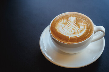 hot latte art in white cup on black background.