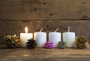 White Advent candle on a rustic wooden background, First candle is burning