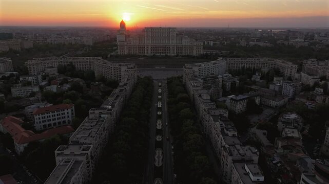 Sunset over Bucharest. Aerial 4K view from above of Palace of the Parliament and Unirii Boulevard during a beautiful sunset. Forward drone camera movement. Travel to Romania.